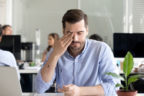 man rubbing his eyes