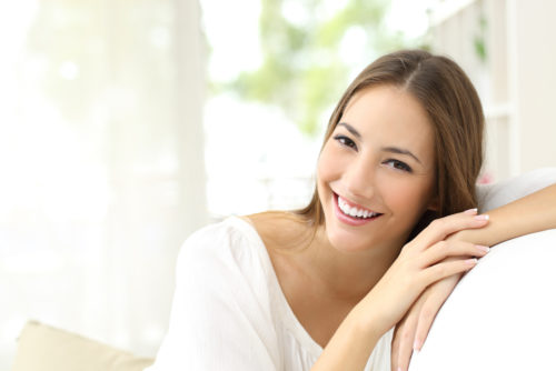 A women smiling while sitting on a white couch 