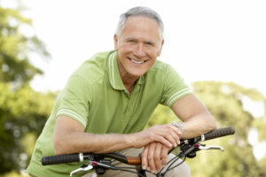 Older male sitting on a bike and smiling 